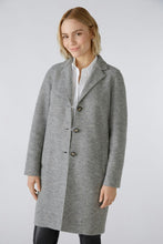 Load image into Gallery viewer, A woman modeling a light gray wool-blend coat with dark buttons, worn over a white collared shirt, against a plain light gray studio background.