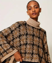 Load image into Gallery viewer, A woman wearing a chunky knit turtleneck sweater with a brown, beige, and black geometric pattern, photographed against a plain light background.