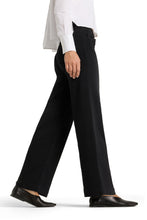 Load image into Gallery viewer, A person wearing black wide-leg trousers with a white long-sleeve shirt and black leather shoes, shown from the waist down in a side-profile walking pose against a white studio background.