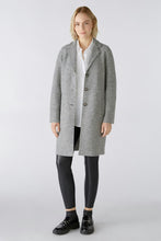 Load image into Gallery viewer, A woman modeling a light gray mid-length coat over a white shirt, black leggings, and black shoes, standing against a light gray studio background.
