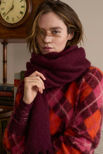 Load image into Gallery viewer, A woman wearing a thick, soft plum-colored knit scarf and a red, orange, and pink plaid sweater, posed in front of a vintage wooden clock and bookshelf.
