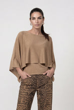 Load image into Gallery viewer, A woman modeling a shimmering tan draped top with wide batwing sleeves, paired with leopard-print pants, against a plain light gray studio background.
