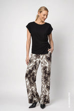 Load image into Gallery viewer, A woman modeling a black short-sleeve top and wide-leg trousers with a brown, black, and white paisley pattern, standing against a light gray studio background.
