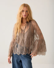 Load image into Gallery viewer, A woman modeling a sheer taupe lace long-sleeve blouse over a matching lace camisole, paired with blue jeans, against a plain off-white studio background.
