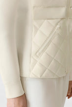 Load image into Gallery viewer, Close-up of a cream-colored jacket with quilted design and zipper detail on a light background
