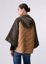 Load image into Gallery viewer, A woman shown from the back wearing a brown hooded quilted vest with plaid sleeves and hood, paired with blue jeans, against a light gray studio background.

