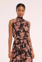 Load image into Gallery viewer, A woman modeling a sleeveless high-neck maxi dress with a black base and a pink and beige floral pattern, set against a plain light background.
