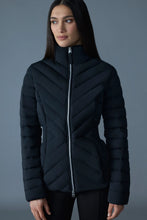 Load image into Gallery viewer, A woman modeling a black quilted puffer jacket with a high stand-up collar and a central silver zipper, set against a solid dark gray studio background.
