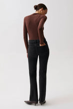 Load image into Gallery viewer, A model shown from the back wearing a brown long-sleeve top, black flare jeans, and dark pointed-toe heels against a plain light gray studio background.
